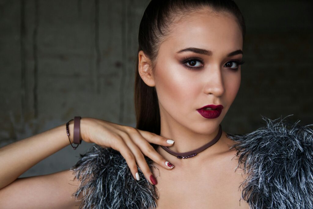 Close-up portrait of an elegant woman with bold makeup and fashionable attire, exuding confidence.